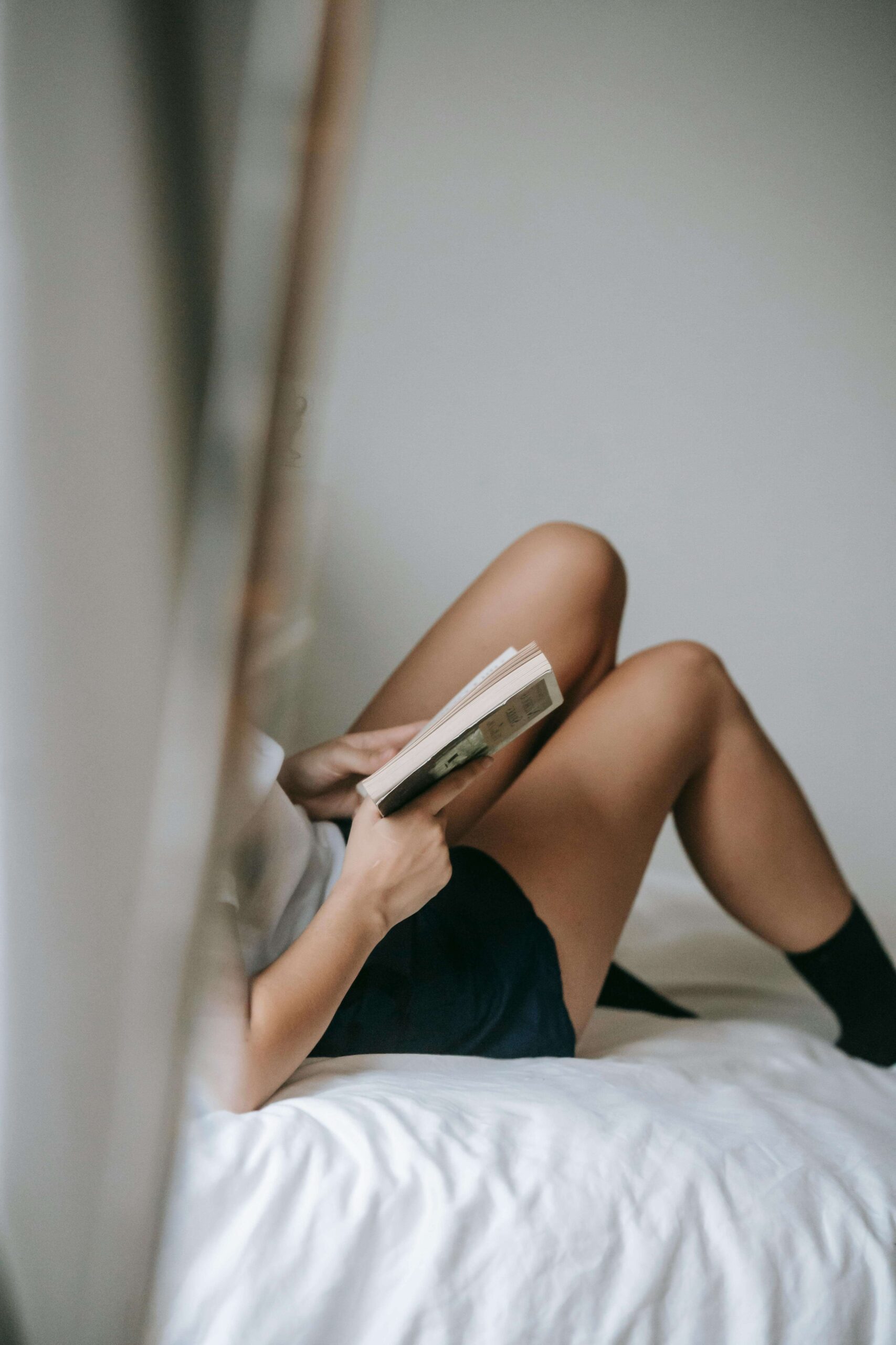 An image of a woman on a bed, reading erotic literature.